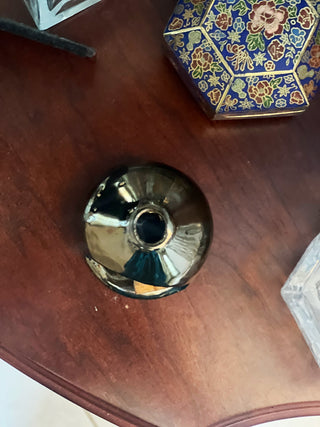 Metallic decorative object on a wooden surface with a colorful box in the background